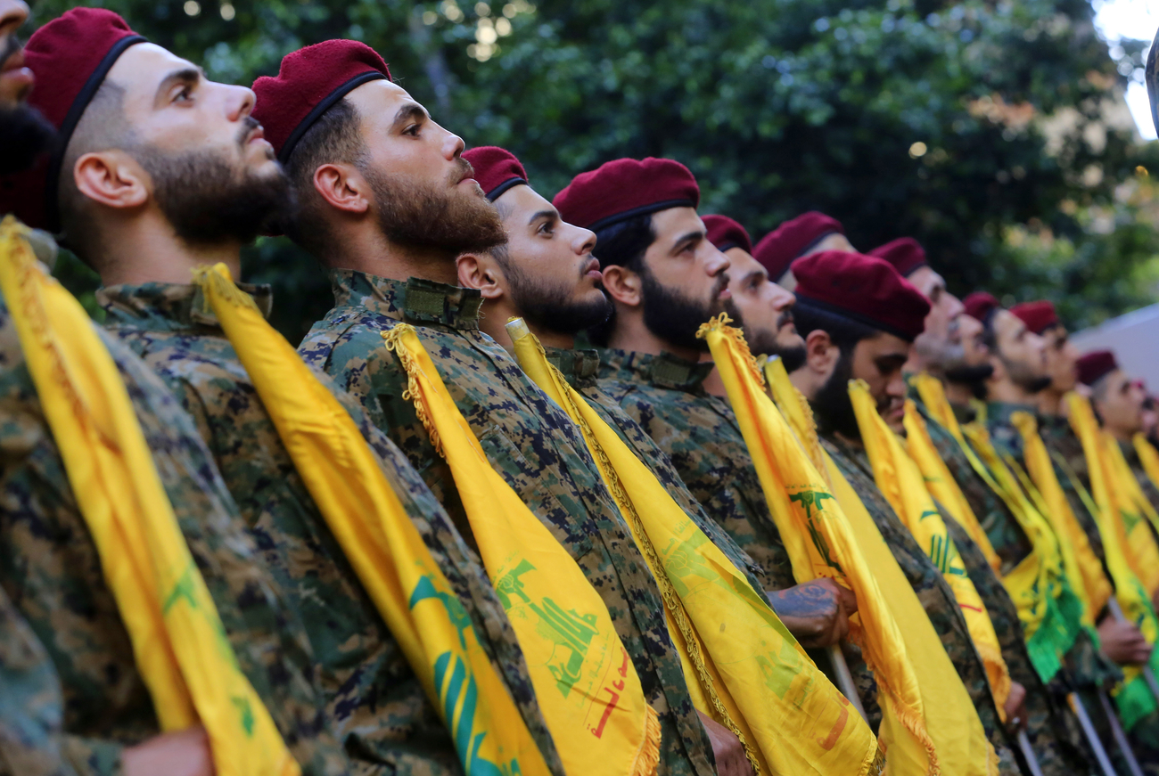 Hezbollah fighters stand at attention with flags