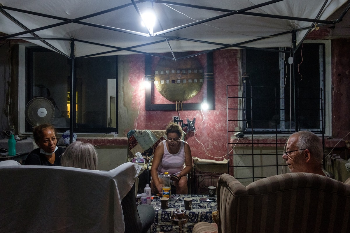 امرأة من سكان الكرنتينا تتشارك القهوة المسائية والعصير مع جيرانها عند مدخل بيتها. كرنتينا، بيروت. ٢٣ أيلول ٢٠٢٠. (ريتا قبلان، مصدر عام)