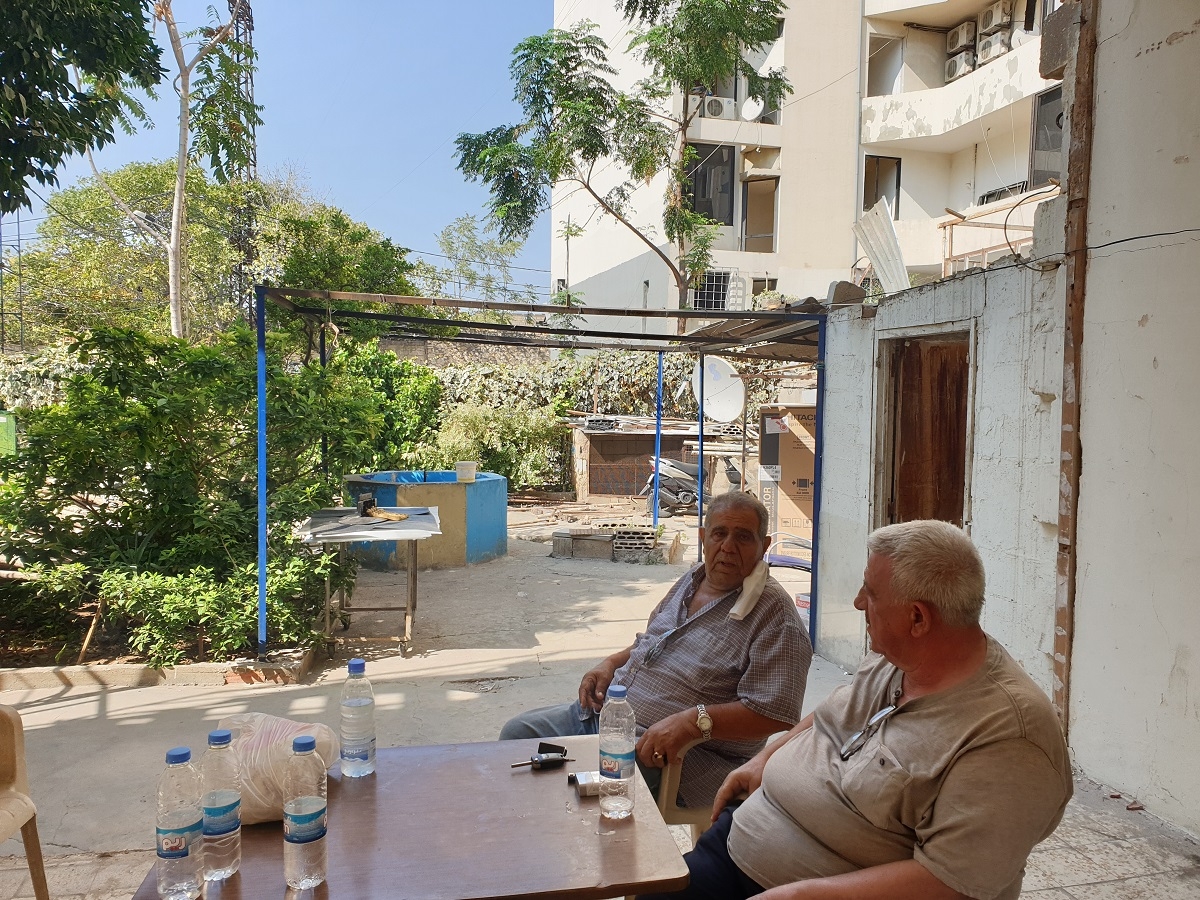 Two men engage in a conversation in front of their damaged house. Karantina, Beirut. August 31, 2020. (Batoul Yassine/The Public Source)