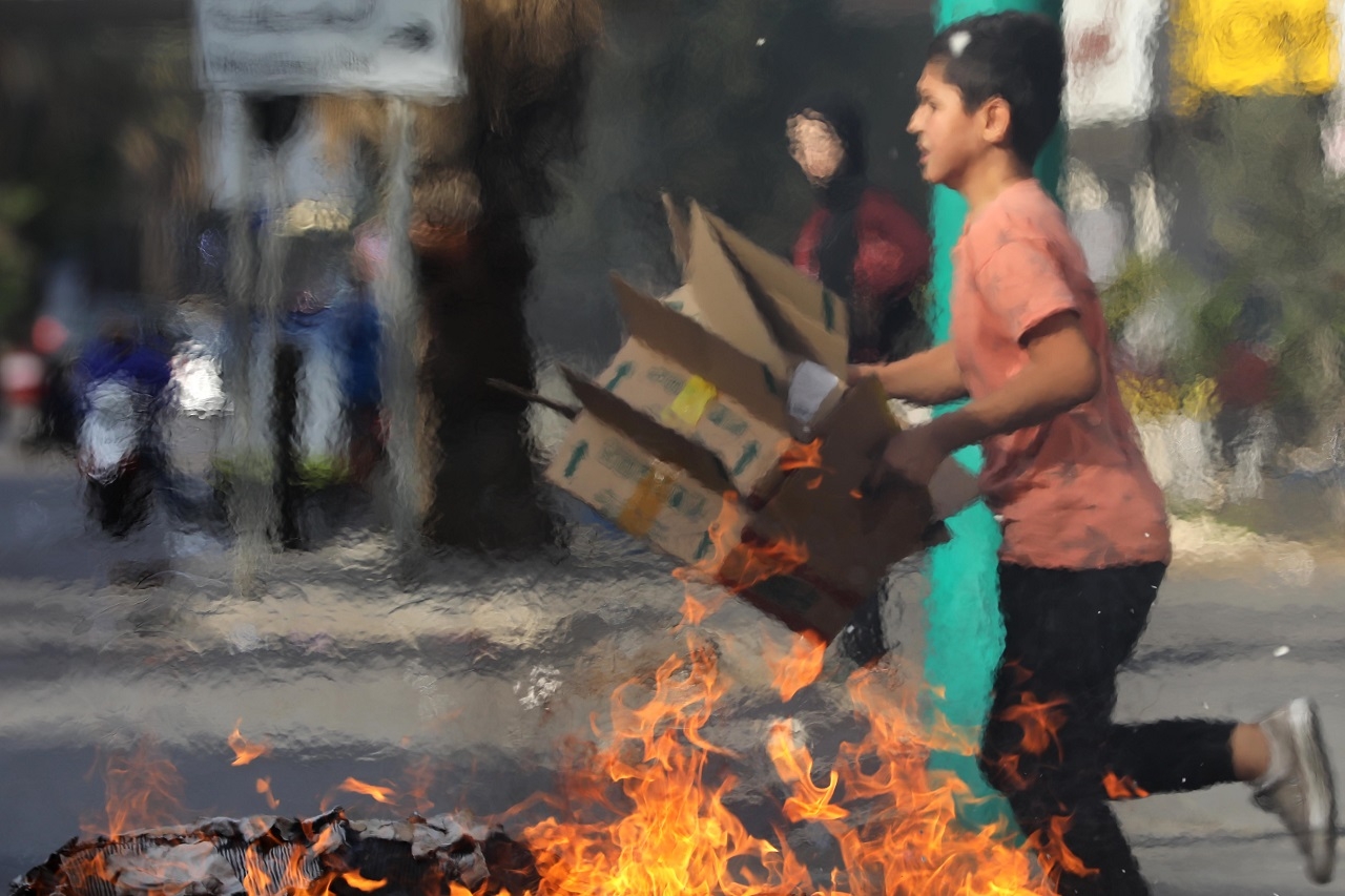 A child runs, cardboard boxes in hand, to help protestors block a main road.