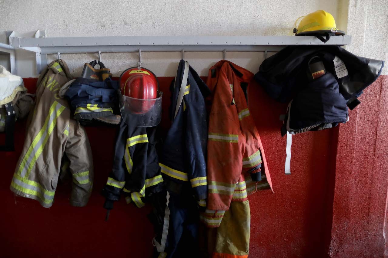 A few red and yellow firefighting suits and helmets hang on a wall at the Beirut Fire Brigade.
