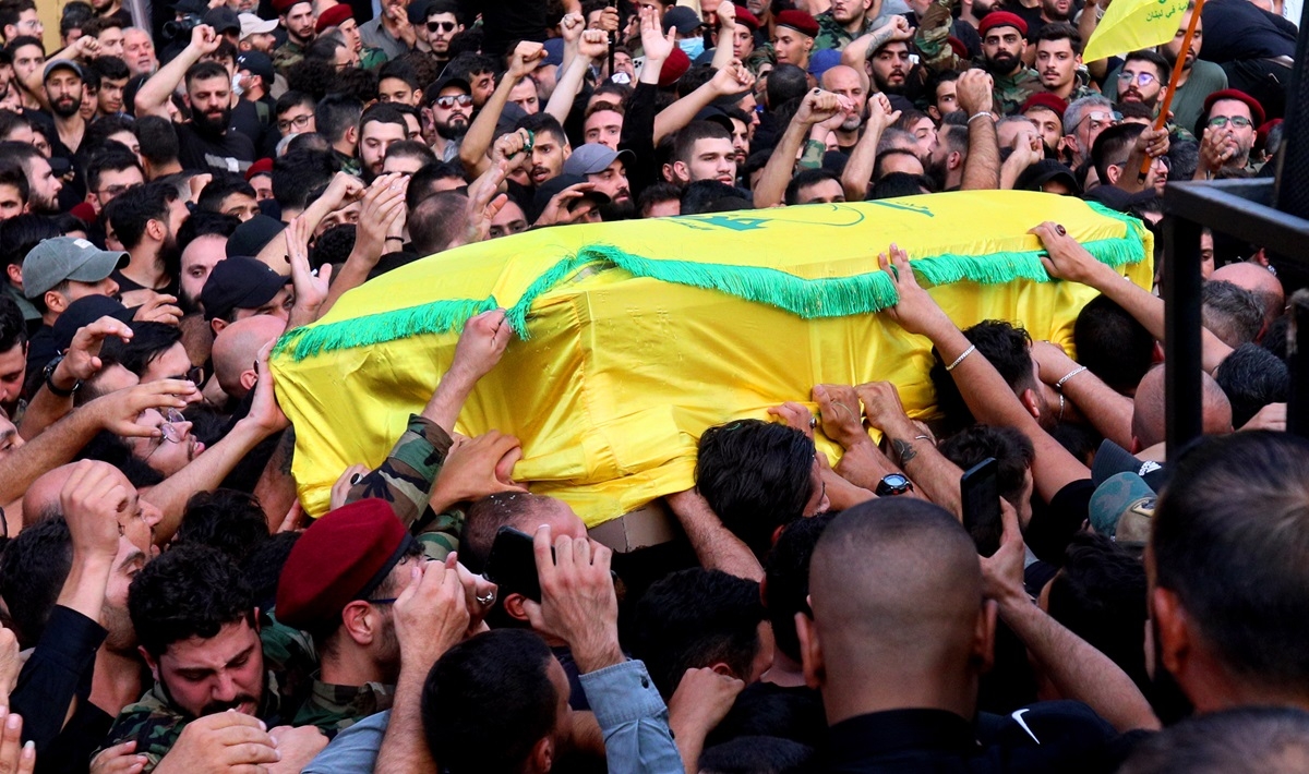 A sea of people carrying a casket, draped in yellow.