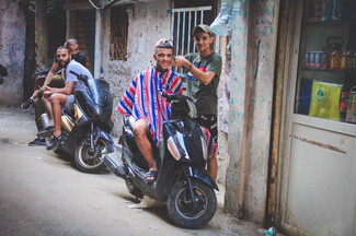 الحلاقة هي من المشاهد الأساسية بالعيد، بس هالمرة مش بالمحل بل بالشارع بسبب انقطاع الكهرباء والشوب.