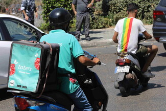 A Toters delivery worker drives through traffic.