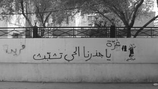 “Ahed Al-Tamimi” is stenciled on a wall next to “Gaza, our living root, hang on”.
