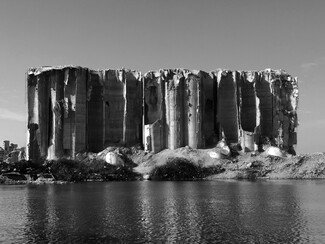 Black and white view from the sea of the destroyed silos.