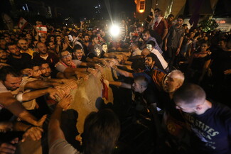 People protest on two sides of a concrete wall.