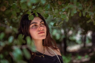 A portrait of a woman amidst trees.
