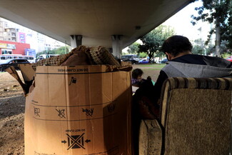 Picture of a man and a young child sitting on old furniture under the Cola bridge.