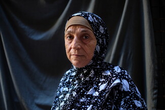 A portrait of a woman standing in front of a black cloth.
