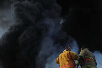 Firefighters face black smoke from a fire that broke out near the silos.