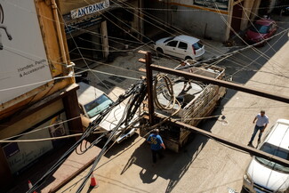 Intertwined electricity and generator cables hang close to the balcony of an apartment in the industrial zone of Beirut