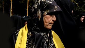A portrait of Hajjeh Zeinab Ali Hussein, Hassan's sister, captured during the funeral procession of the martyred family.