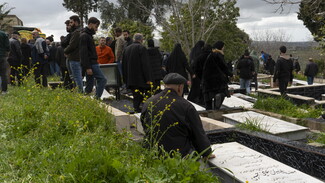 Landscape view of Houla's cemetery, people gathering to pay their respect to the martyred family carried in the yellow coffins to their final resting place.