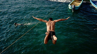 A young man dives into the water of Dalieh. 