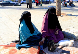 Two displaced women sit with their cat on the streets of Beirut. 