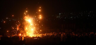 A nighttime airstrike causes an explosion over a dark town.