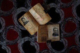 Two open booklets with handwritten text and black-and-white photos on a patterned surface.