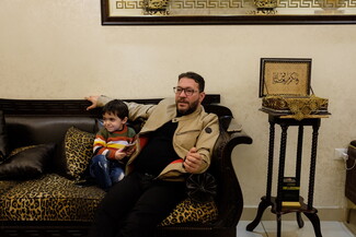 A man and a child sit together on a leopard-print couch.
