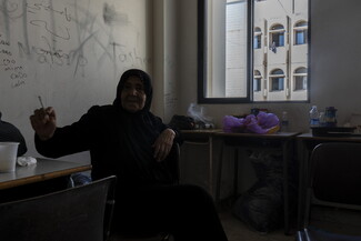 امرأة تدخّن سيجارتها في أحد الصفوف الذي تحوّل إلى بيت مؤقت داخل مركز النزوح في مجمّع بير الحسن. بيروت لبنان. ٣ أكتوبر، ٢٠٢٤. (مصدر عام/فاطمة جمعة)