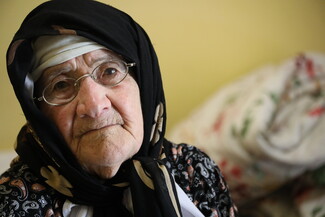 A veiled older woman looks into the camera.