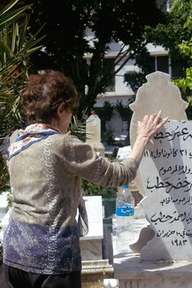A woman commemorates her family members buried in Bachoura Cemetery. 