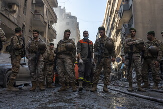 جنود من الجيش اللبناني وعنصر من الدفاع المدني يقفون أمام المبنى المستهدف في شارع فتح الله. بيروت، لبنان. ٢٣ كانون الأول، ٢٠٢٤. (مصدر عام، فاطمة جمعة)