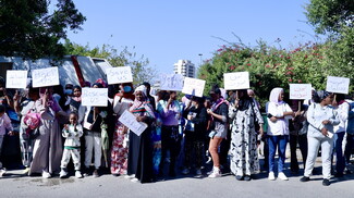 A group of women holding up signs to the camera, that read "Help us," "Rescue us," "Save us," and "we are dying."
