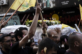 Men hold up a casket at a funeral.