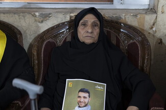 An elderly woman holds a photo of a martyred man.
