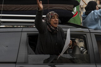 امرأة ترفع شارة النصر من شباك باص للعائدين إلى الضاحية الجنوبية. ٢٧ تشرين الثاني، ٢٠٢٤. الضاحية الجنوبية. (مصدر عام، فاطمة جمعة)