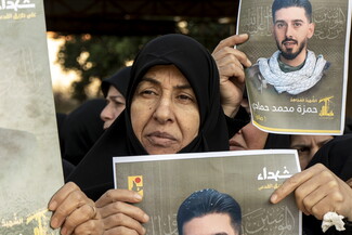 أم حمزة تحمل صورة ابنها الشهيد في تشييعه في قرية الصوانة. الجنوب، لبنان. (فاطمة جمعة، مصدر عام)