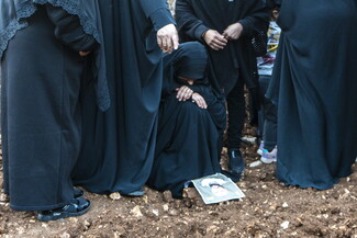نساء يتحلقن حول أم حمزة الجاثية على صورة ابنها وقبره في الصوانة، جنوب لبنان. جبل عامل، لبنان. (فاطمة جمعة، مصدر عام)