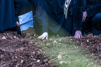 يد أم الشهيد تمسح على تراب قبره. الصوانة، لبنان. (فاطمة جمعة، مصدر عام)