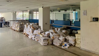 Stacks of papers piled up inside a ministry building, in front of clerks' desks.