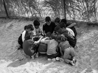 A group of children gather together for safety and companionship on the sands of Rafah, in the Gaza Strip.