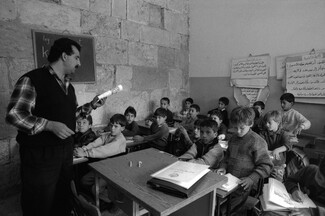 A black and white photo of a male teacher reading to his primary school classroom in Jerusalem.