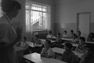 A photo of a female teacher interacting with students at an UNRWA school in Ramallah.