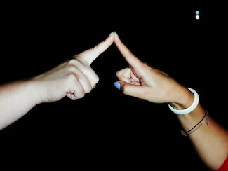 Two hands are held up in the frame with their pointer fingers touching