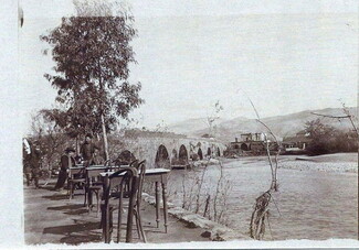 Old postcard of the Beirut River in Lebanon, showing people seated on small tables and chairs along its banks.