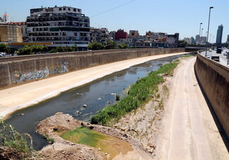 The Beirut River shows murky green and brown patches of sewage and contamination.