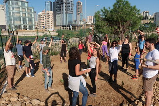 People dancing on a vacant lot in the middle of the city, with tall concrete buildings rising in the background.