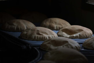 Freshly baked Arabic bread sits on a rack to cool.