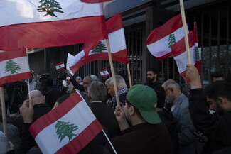 Protestors marching on Hamra Street carry flags, banners, posters, and photos of martyred and detained loved ones.