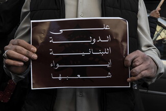 A survivor of the Israeli pager attack holds up a poster that reads: “The Lebanese state must shelter its own.”