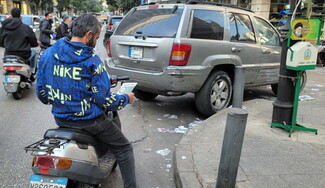 A man on a motorcycle looks down at a leaflet, dropped on Souk el-Dahab, Barbour by Israeli military.