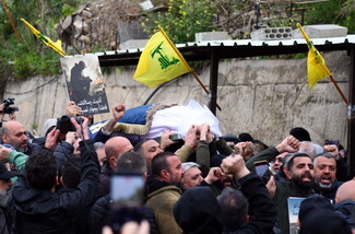 Mourners carry a coffin through a crowd in Dahieh, Beirut, as Hezbollah flags wave above and people raise their fists and hold photos.