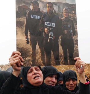 Woman holding the photo of martyred journalists, Ali Shoeib, Fatima and Mohammad Ftouni.