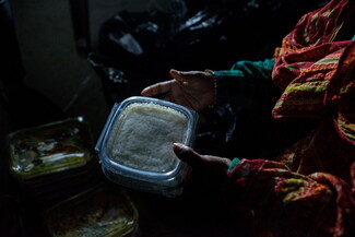 A woman's hands holding a plastic box with rice inside. 