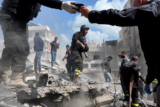 Civil Defense and other responders join forces to rescue people trapped under the rubble following the Hay al-Raml/al-Raml neighborhood strike in Sur. A Civil Defense member’s hand is seen taking a cellphone from another, as people check on one another in the aftermath of the strike. It is one of more than 160 strikes—the largest Israeli wave of fire attacks on the country since the beginning of the genocidal campaign on Palestine and Lebanon in October 2023. 
